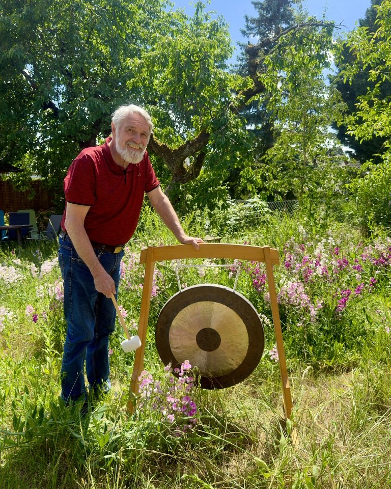 Hermann mit dem Gong zwischen den Blumen im Garten